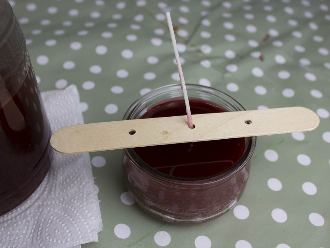 Geschmolzenen Wachs aus alten Kerzen in ein Glas mit Docht füllen